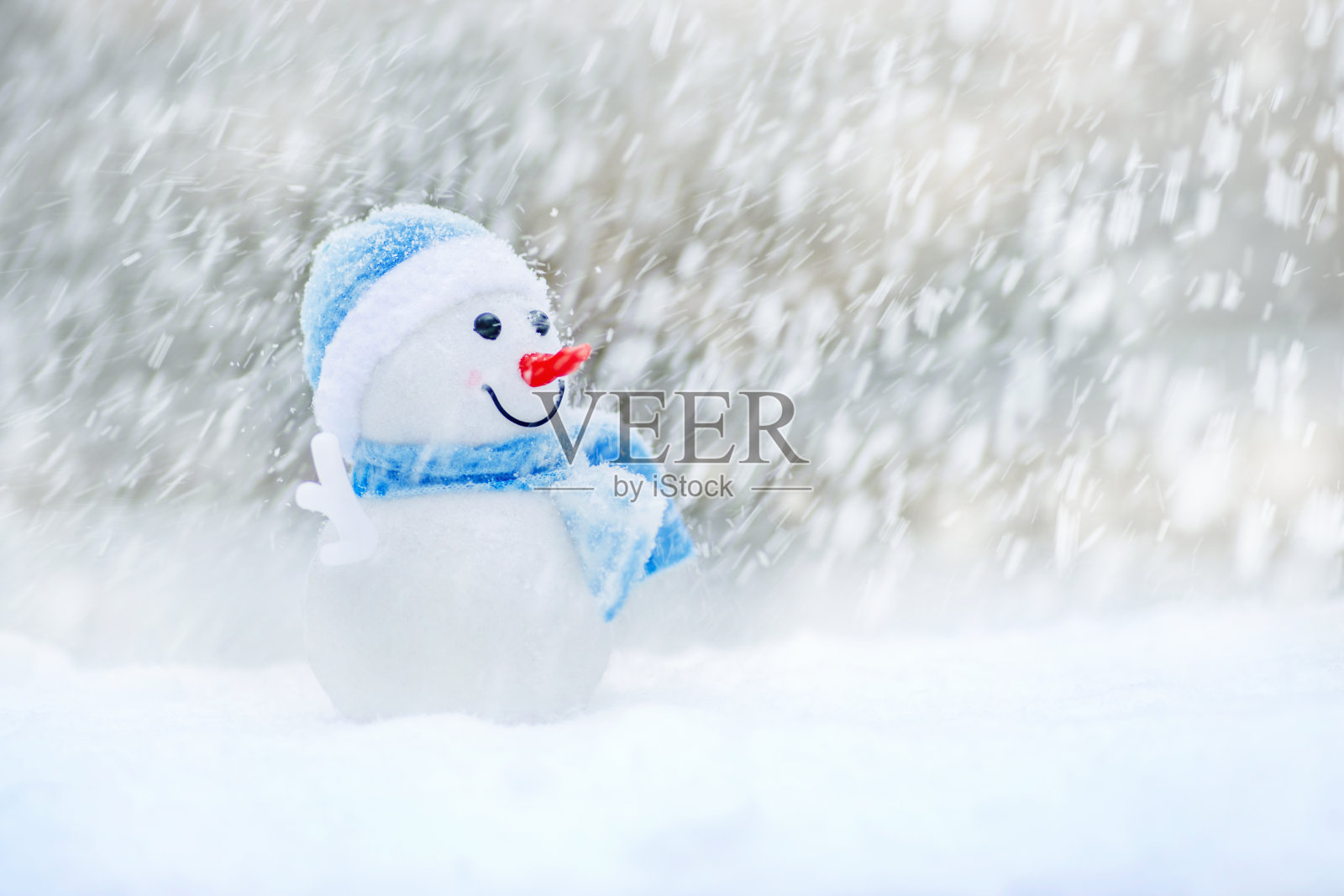 戴着帽子和围巾的圣诞雪人。雪中的雪人玩具。照片摄影图片