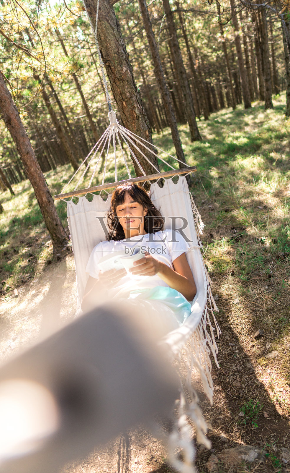 女人在森林吊床上看书照片摄影图片