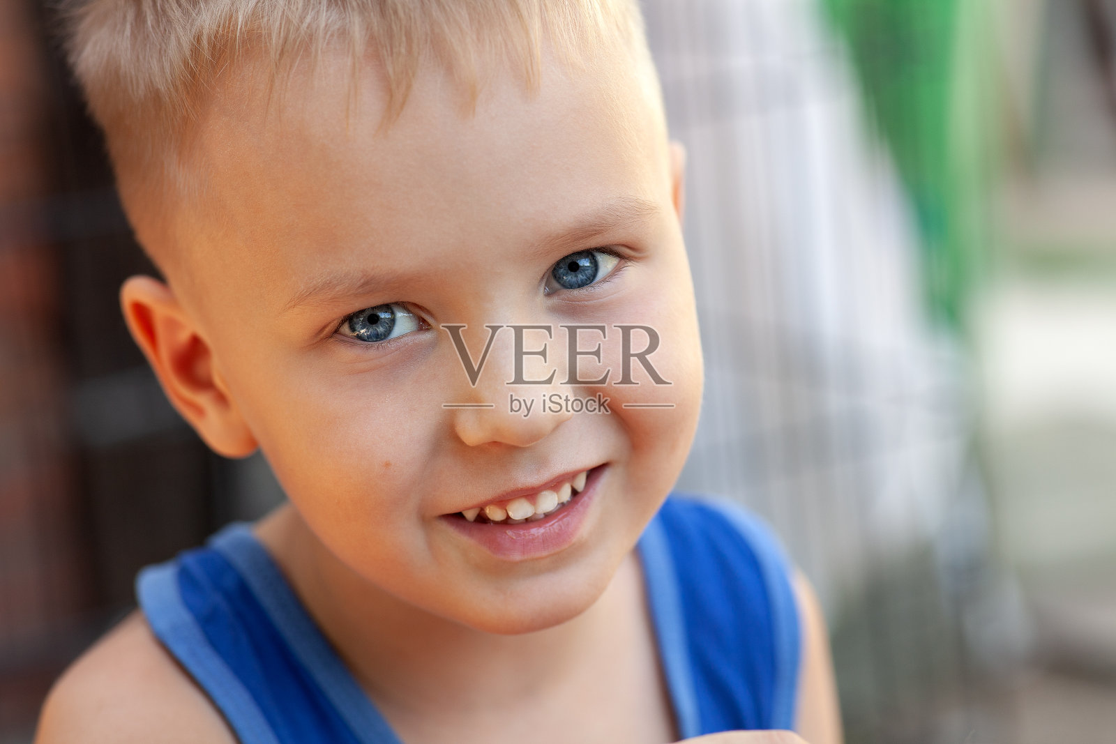 近距离的肖像可爱的小白人男孩与金发和蓝眼睛，微笑。照片摄影图片