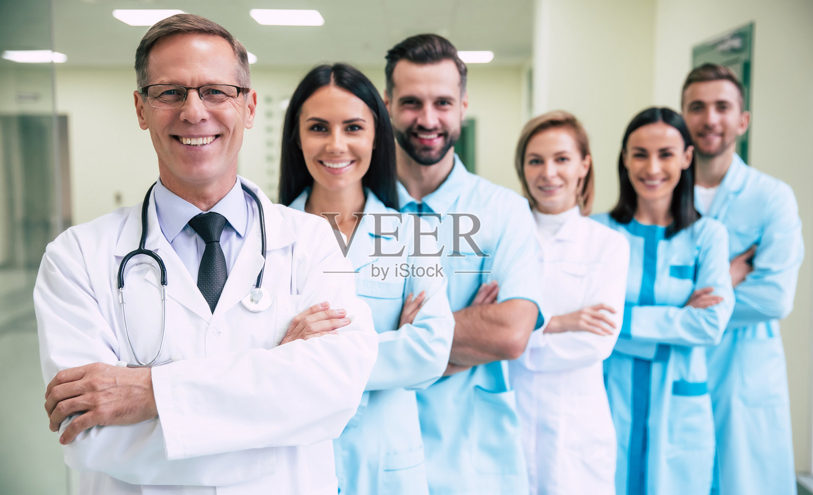 快乐的团队成功和自信的现代医生摆姿势，看着医院走廊的摄像机照片摄影图片