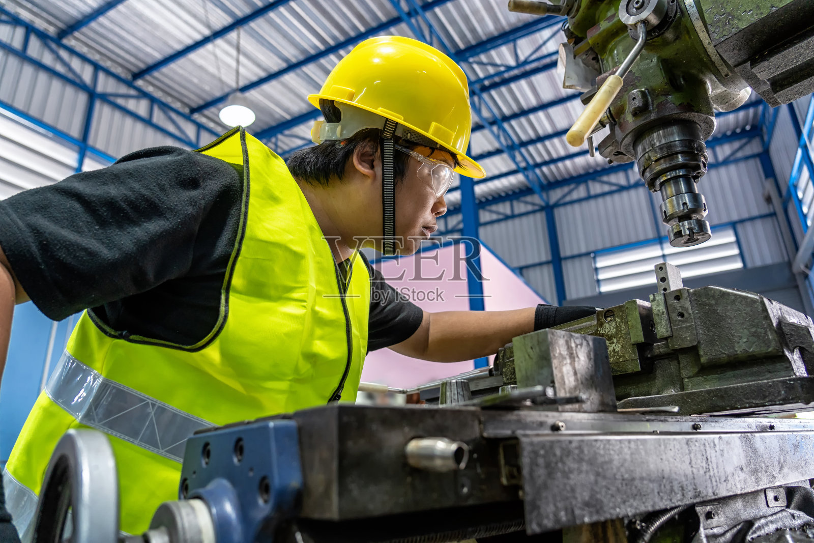 亚洲安全服机械师在金工工厂操作专业车床，车床打磨金工行业概念照片摄影图片