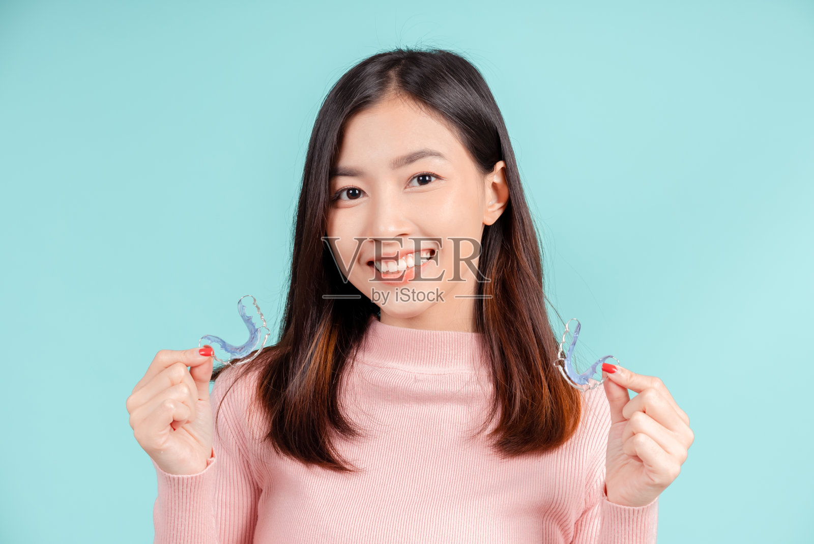 牙齿美丽的微笑年轻的亚洲妇女与牙套，愉快的情绪与白色的牙齿增加信心，健康在蓝色背景孤立，快乐的青少年面部表情。照片摄影图片