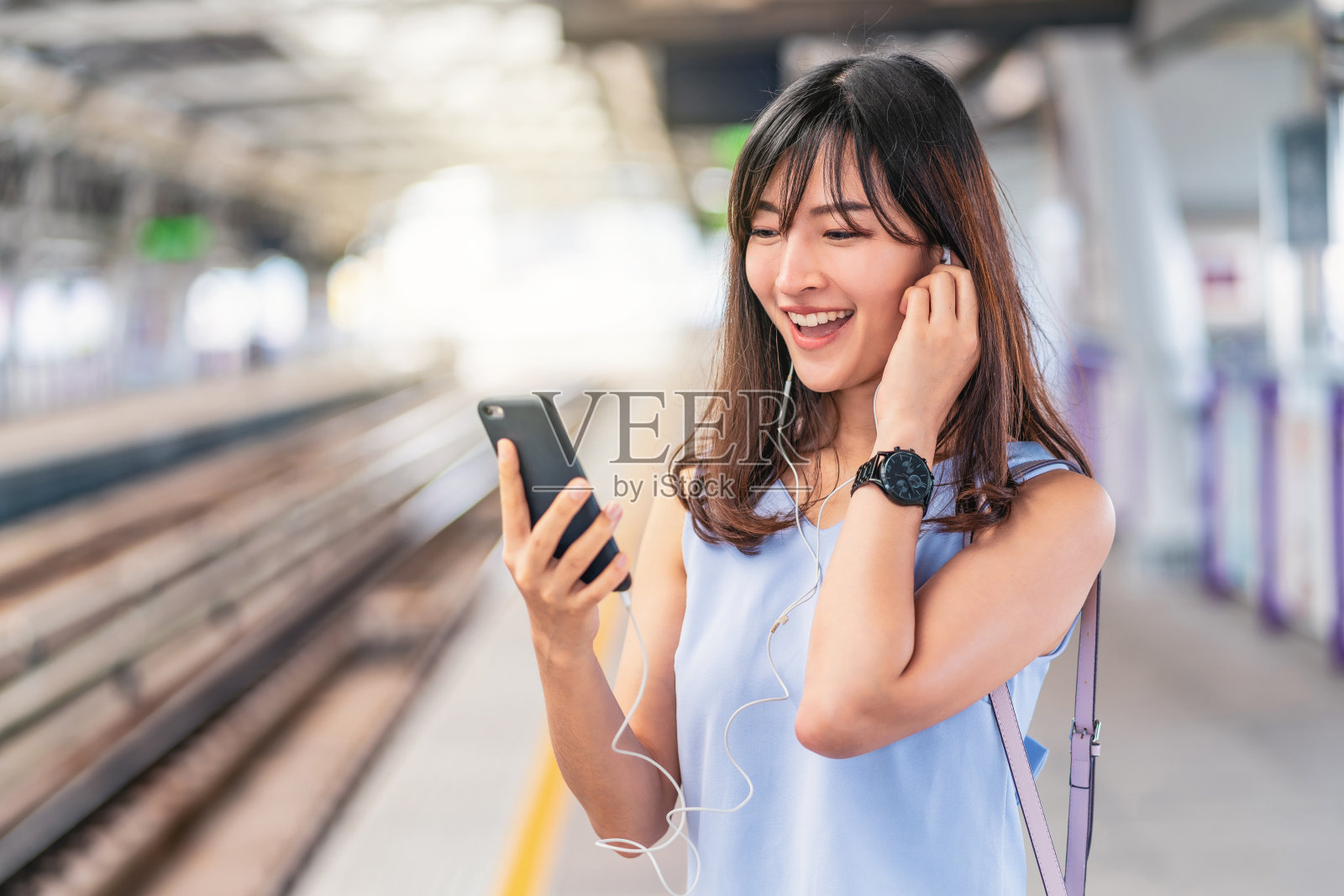 年轻的亚洲女性乘客在地铁上通过智能手机听音乐，在大城市旅行，日本，中国，韩国的生活方式和日常生活，通勤和交通理念照片摄影图片