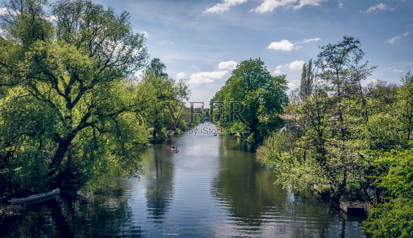河流景观与绿色的树木旁边，船和倒影在水中在夏季照片摄影图片
