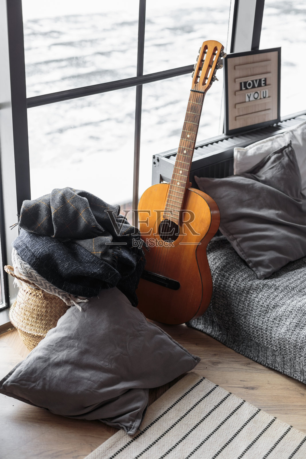 靠近窗户的床上有一把木吉他照片摄影图片