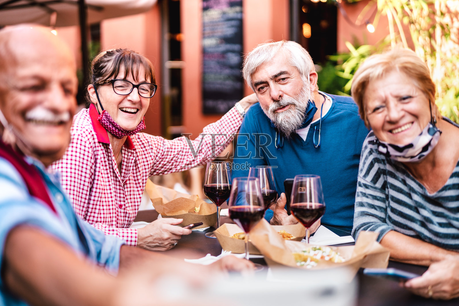 快乐的老年人朋友在餐厅自拍与开放的面罩-退休的人一起在酒吧关闭后重新开放-积极的老年人生活方式概念生动的温暖过滤器照片摄影图片