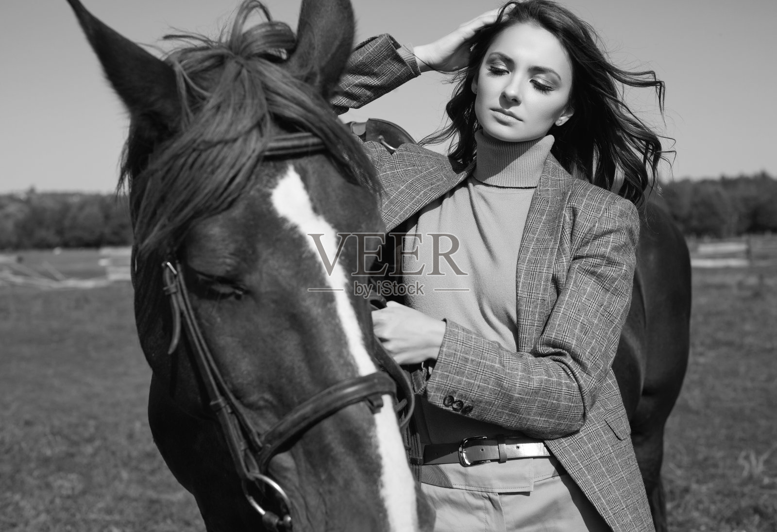 漂亮的黑发女人穿着优雅的格子夹克和一匹马照片摄影图片