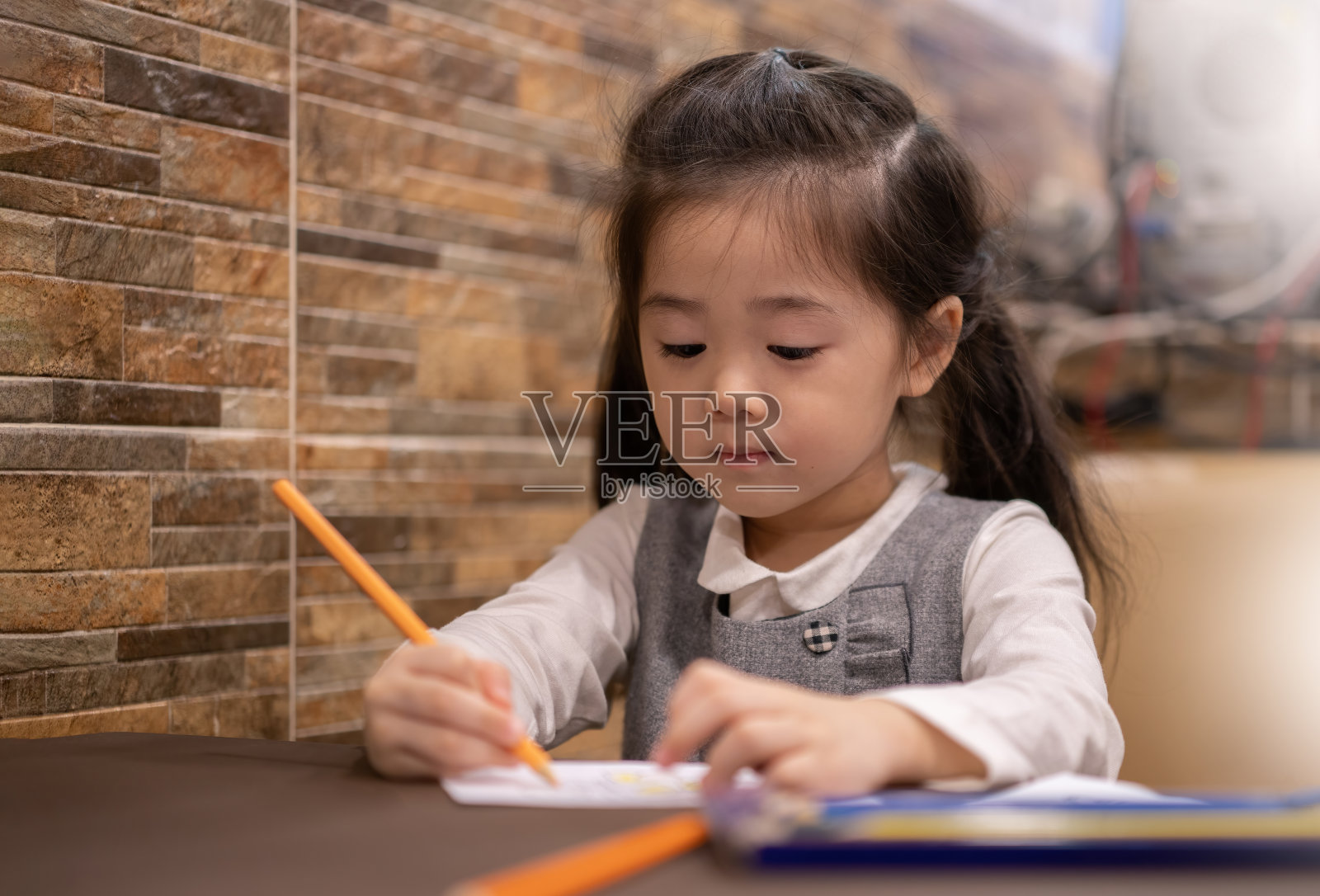 回到学校。快乐微笑的小学生在课桌上画画。可爱的学龄前儿童在家画画。小女孩用铅笔画画照片摄影图片