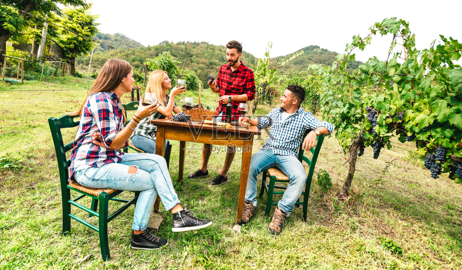 快乐的人们在葡萄园里畅饮红酒-年轻的朋友们在乡村的农舍里一起享受收获的时光-年轻的生活方式概念在温暖的过滤器上照片摄影图片
