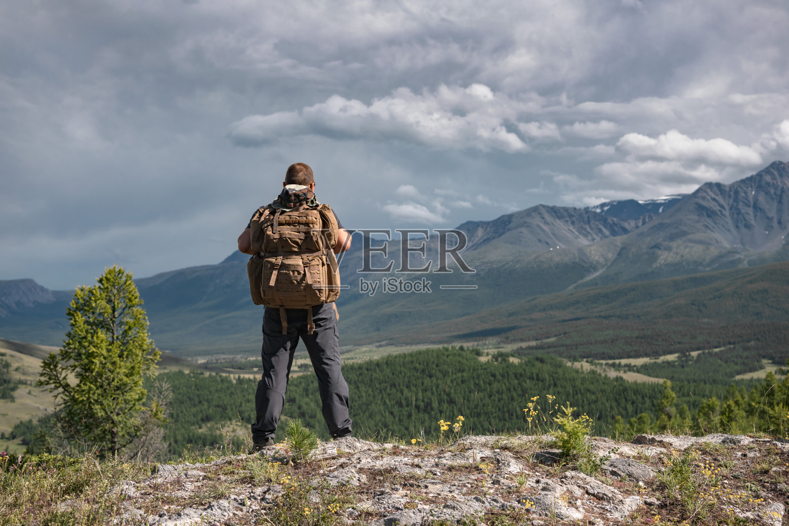 徒步旅行者背着背包站在群山的背景上照片摄影图片