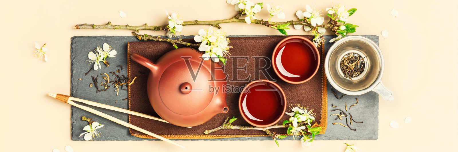 亚洲茶集石板，陶瓷茶壶，杯，干茶和春枝照片摄影图片