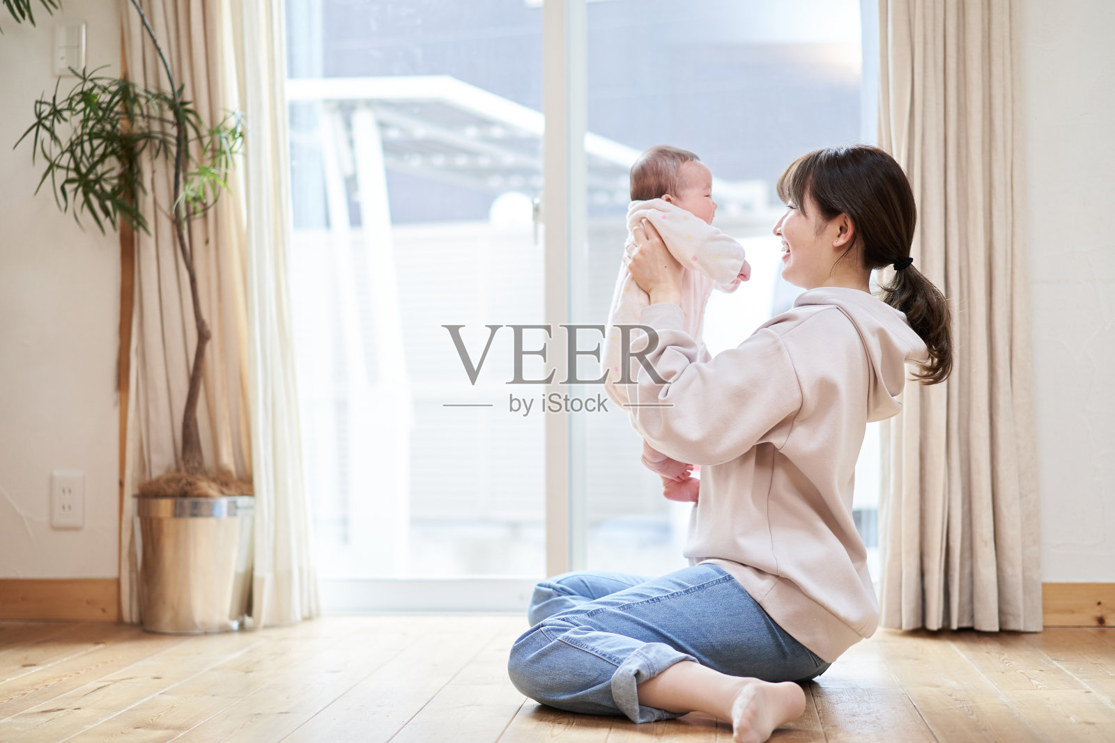 一个亚洲妈妈抱着一个婴儿在客厅里照片摄影图片