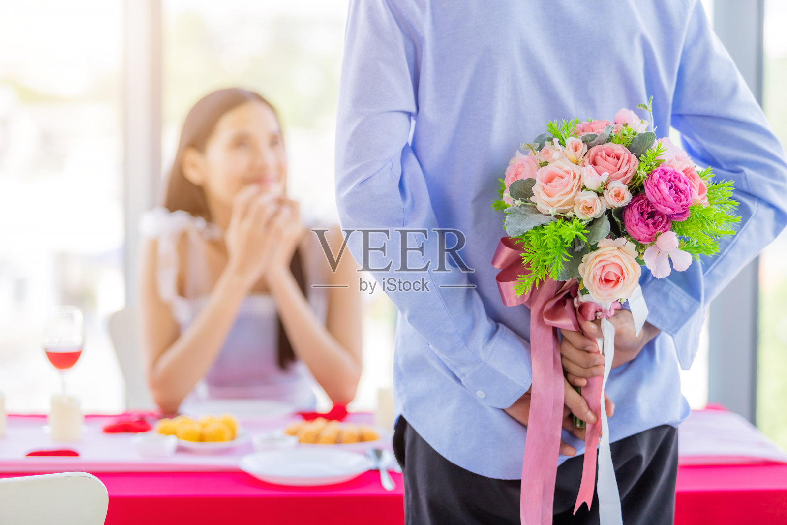 情人节和亚洲年轻幸福的夫妇概念，近距离的亚洲一个男人拿着一束玫瑰女人的手捂着她的脸等待惊喜午餐后在一个餐厅的背景照片摄影图片
