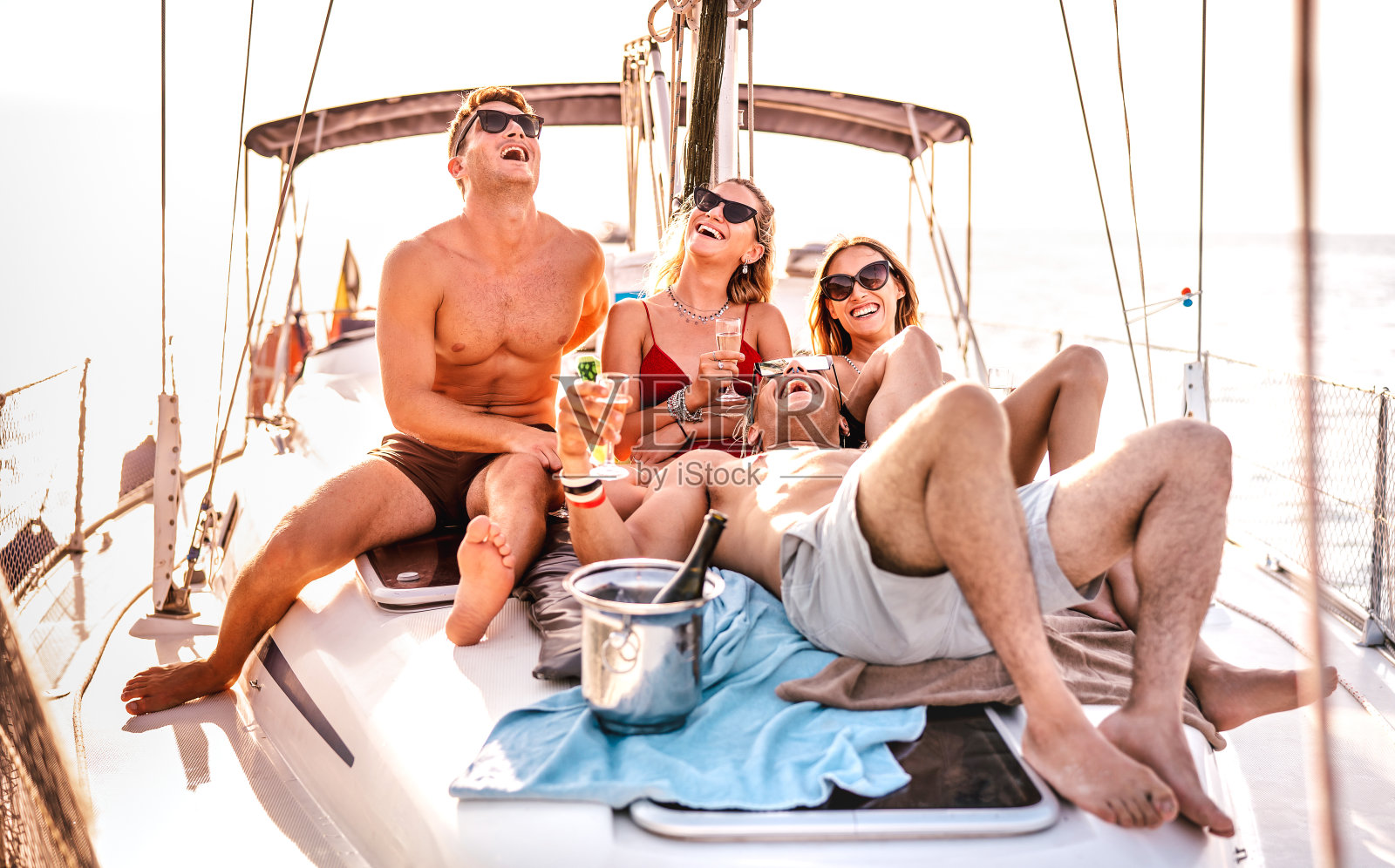 快乐的年轻朋友在帆船派对上玩得开心- Wanderlust旅游概念与千禧年的人在航海旅行-奢侈的生活方式在专属的夏季心情-温暖的阳光光环过滤器照片摄影图片
