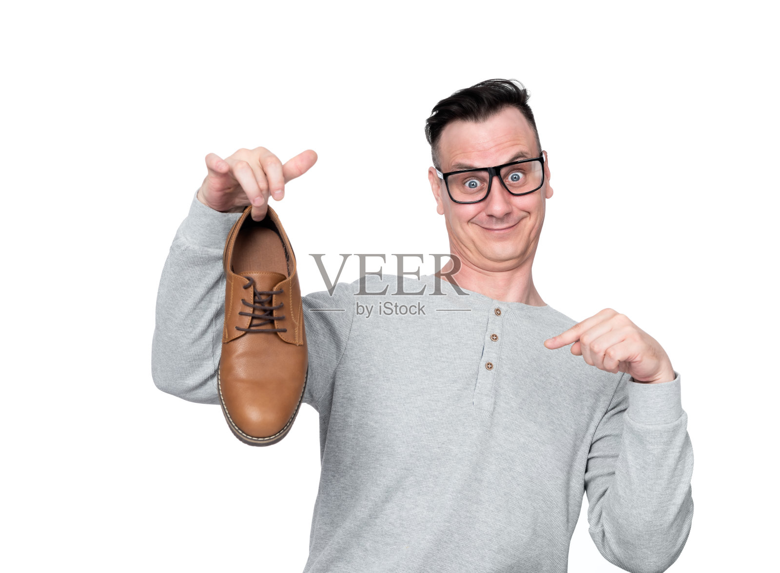 戴眼镜的滑稽男子一只手拿着一只鞋，另一只手用手指指着它，孤立在白色背景上。照片摄影图片