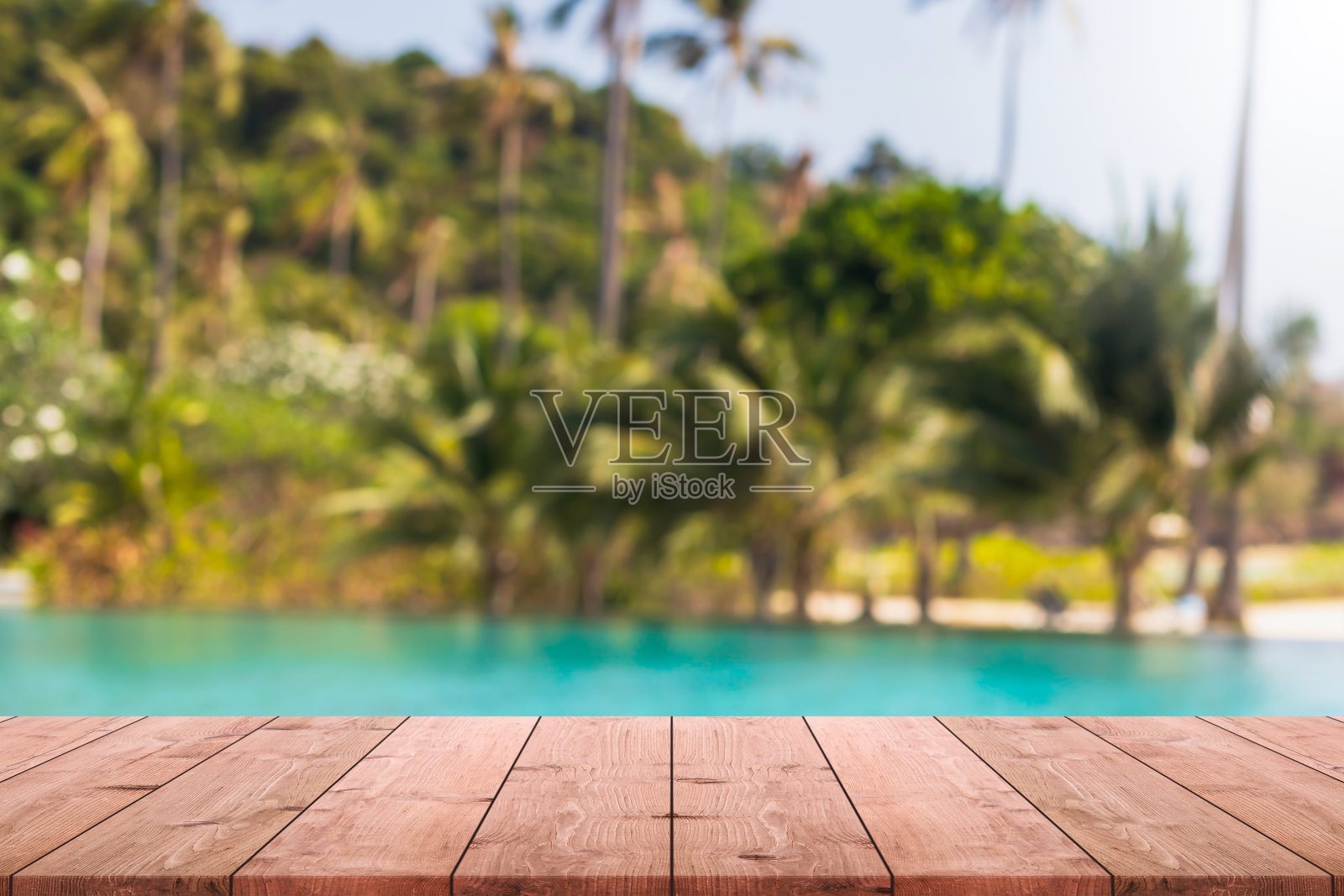 空的木头桌面和模糊的游泳池在夏季的热带度假胜地横幅背景-可以用来展示或蒙太奇您的产品。照片摄影图片