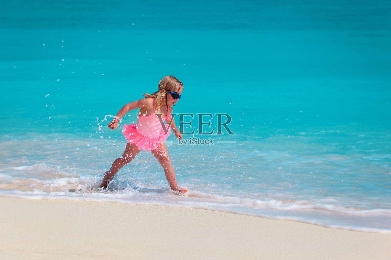 快乐的小女孩在沙滩上玩水，全家度假照片摄影图片