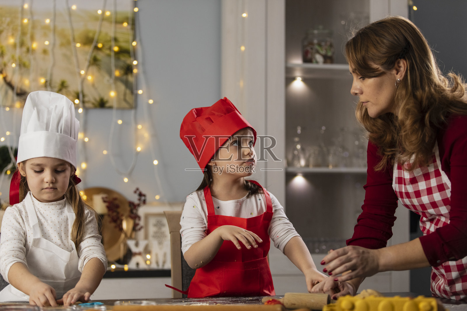 妈妈和两个小女孩在为圣诞节做姜饼照片摄影图片