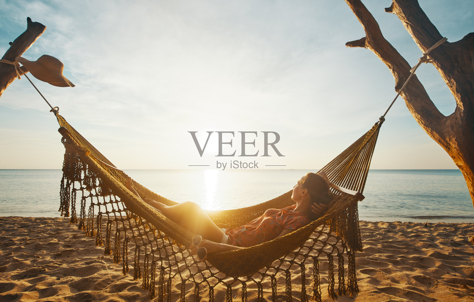 度假海滩夏季度假概念。日落时分，年轻女子在越南富国岛的吊床上休息照片摄影图片