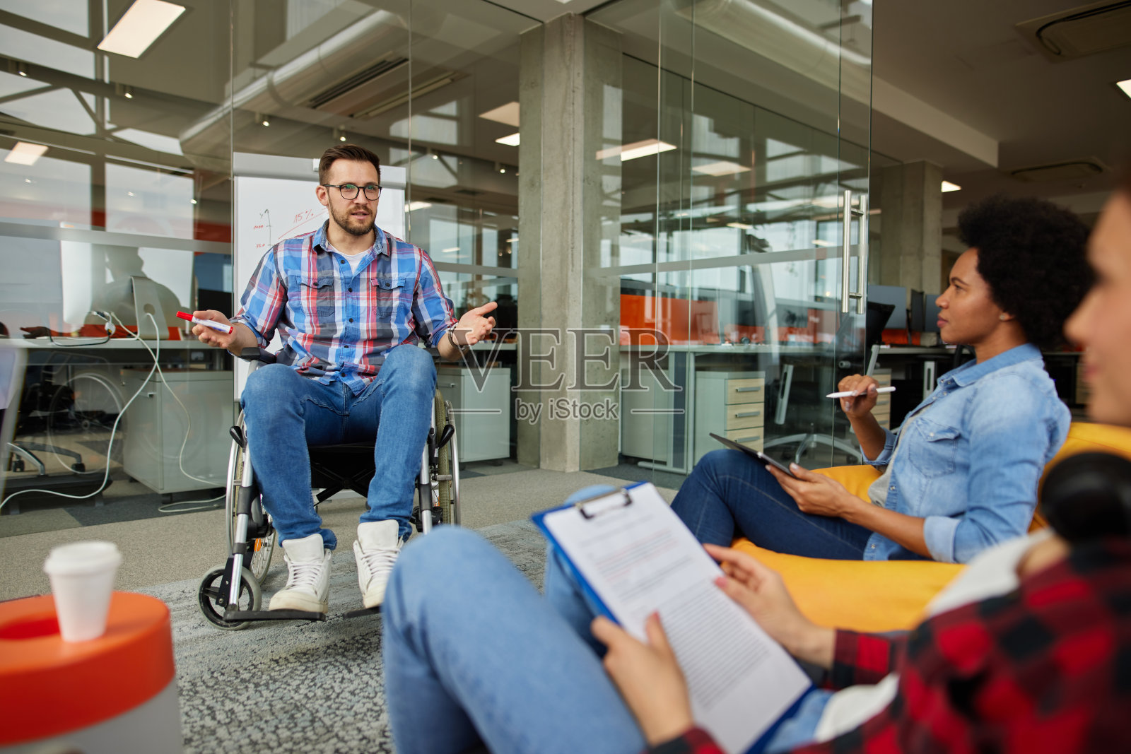 一个坐在轮椅上的程序员在一个现代化的办公室里讨论商业时刻照片摄影图片