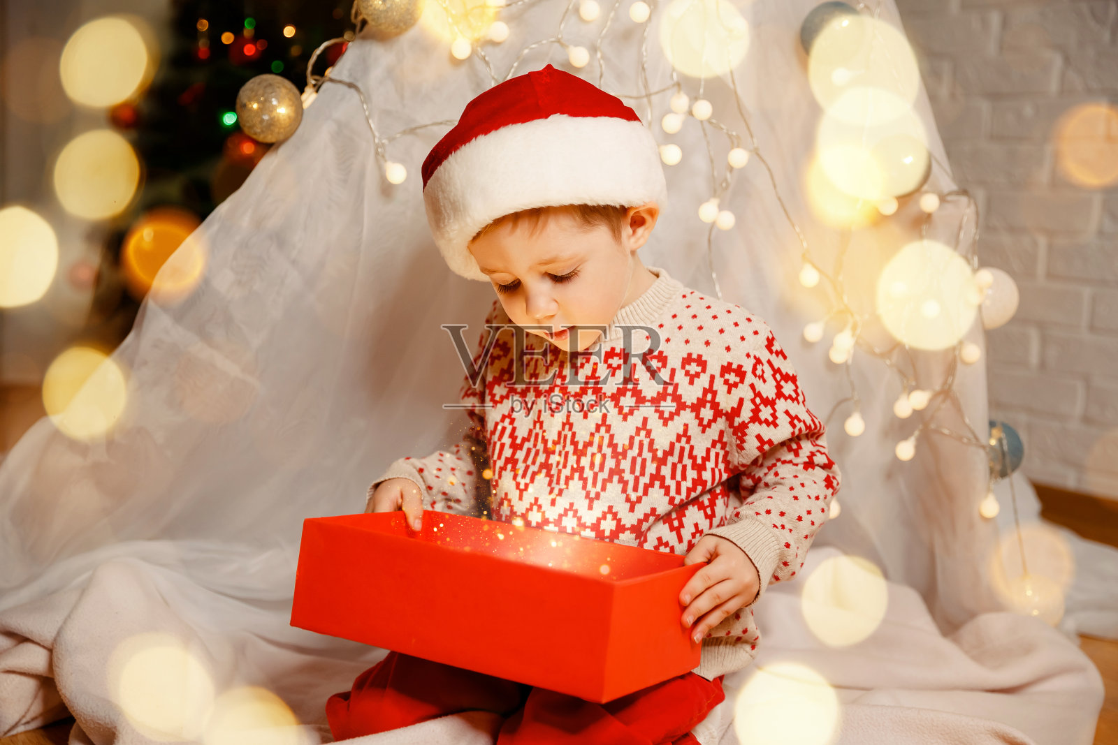 圣诞快乐。快乐的孩子带着魔法礼物靠近圣诞树。照片摄影图片