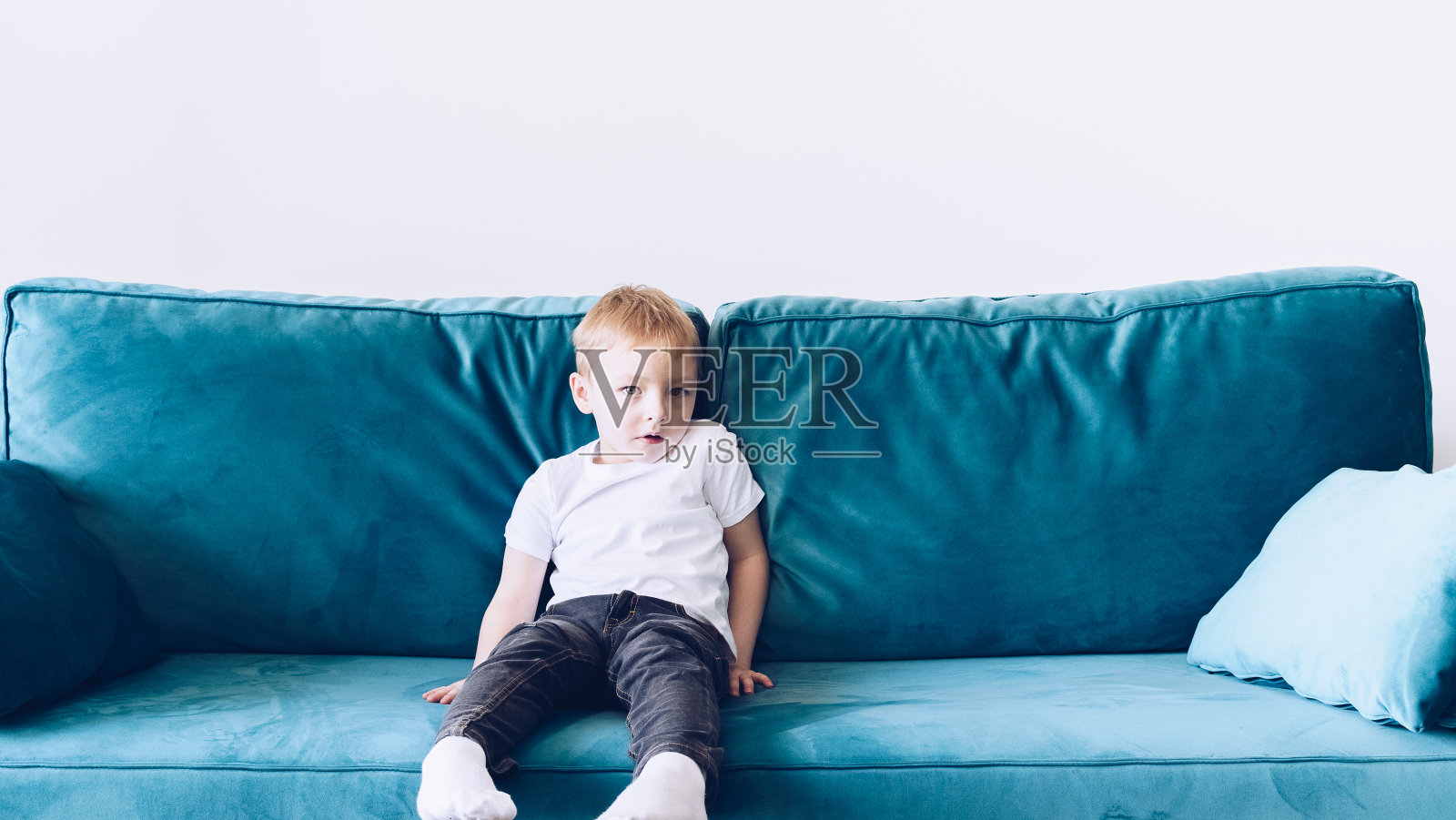 小男孩坐在沙发上照片摄影图片