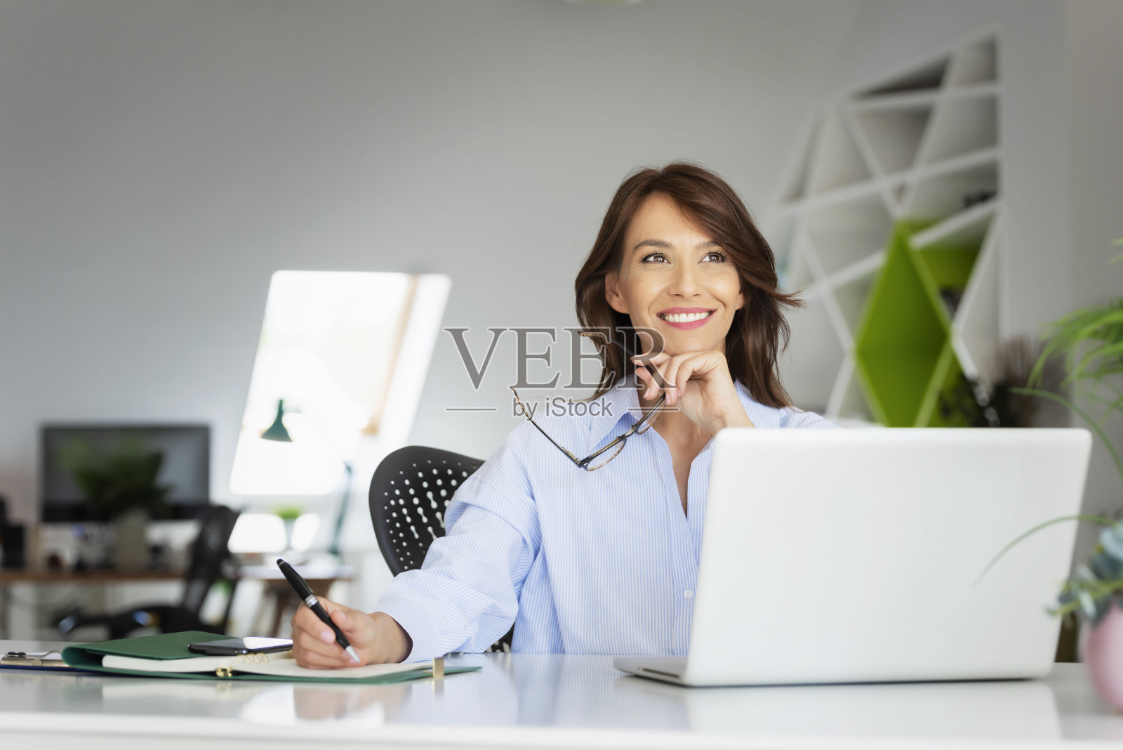 自信的中年女商人在办公室用笔记本电脑工作照片摄影图片
