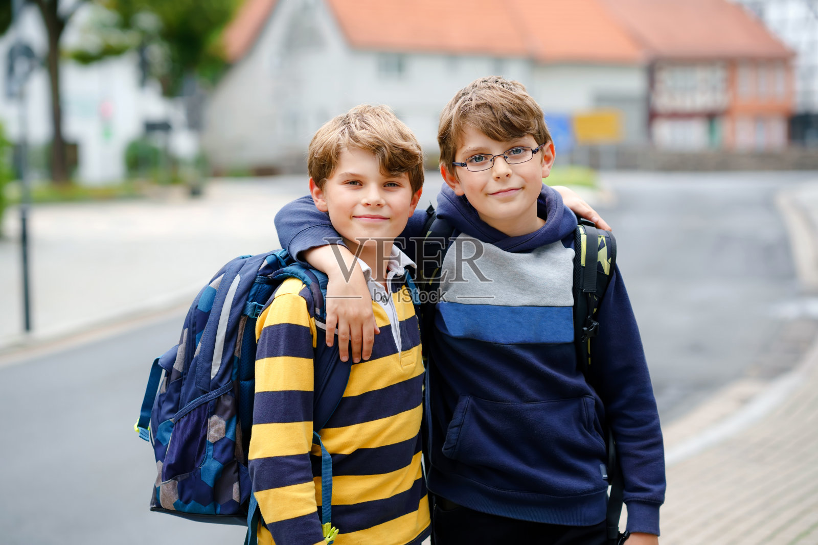 两个男孩背着背包或背包。孩子们在上学的路上。健康微笑的孩子，兄弟和最好的朋友在户外离开家。回到学校。快乐的兄弟姐妹。照片摄影图片