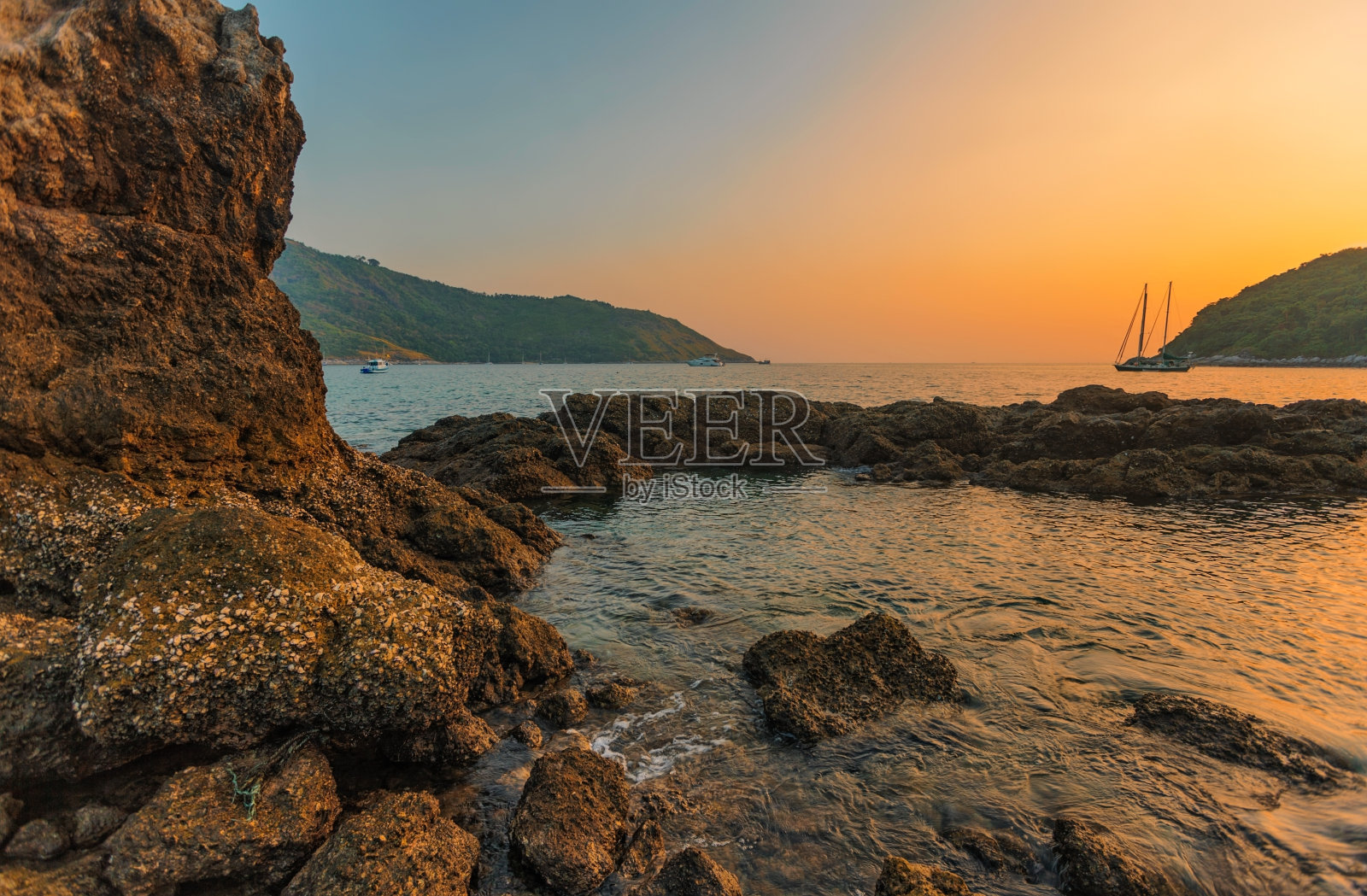 岩石海滩上美丽的日落。照片摄影图片