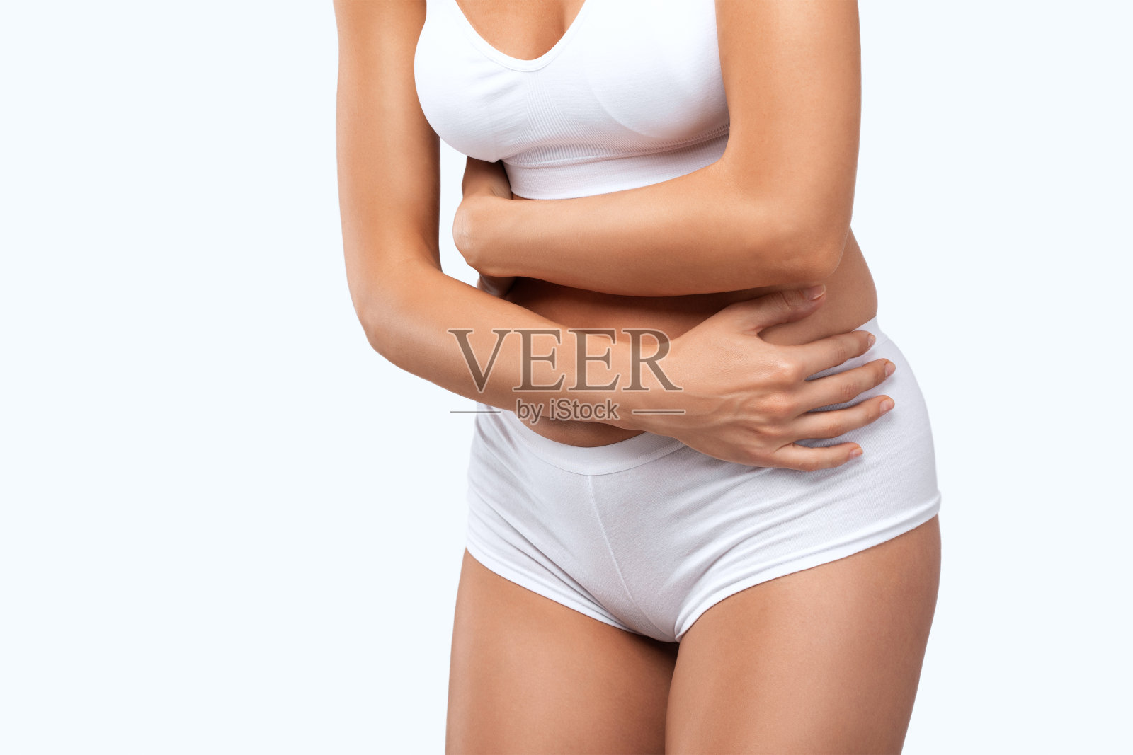 一个穿着白色内衣的苗条美丽的女人正抱着她的肚子，她胃痛。照片摄影图片