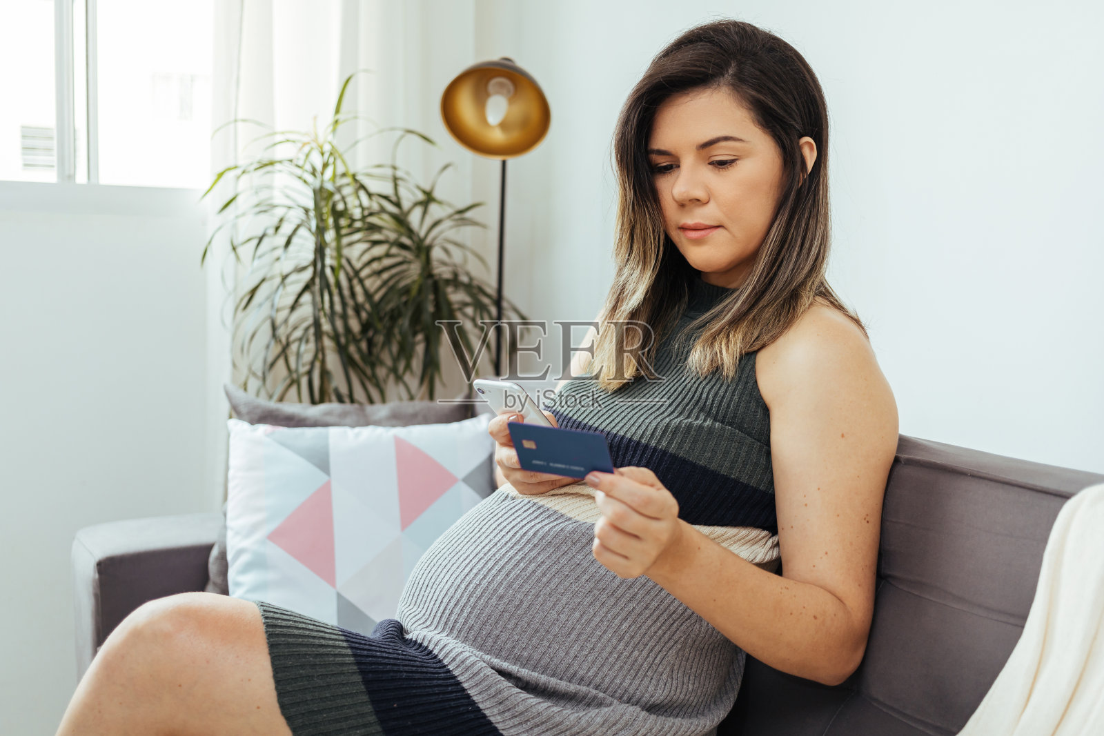 网上购物的概念。孕妇用智能手机和信用卡在网上购买婴儿用品照片摄影图片