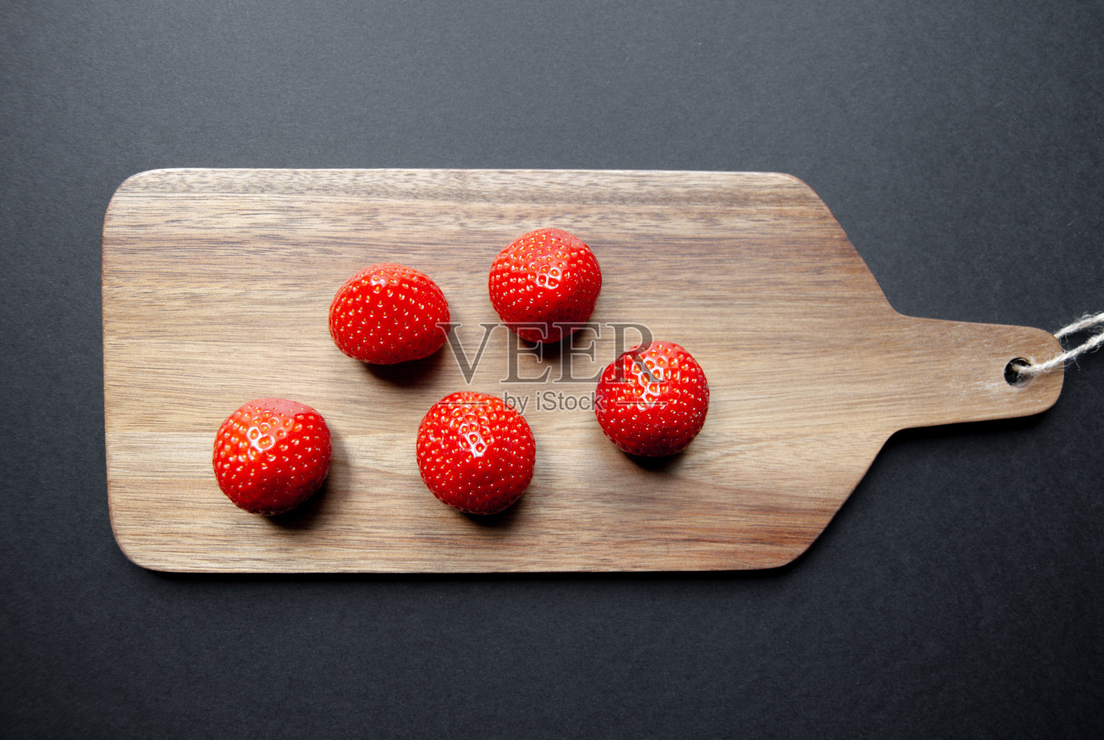 切菜板上的草莓。黑色背景照片摄影图片