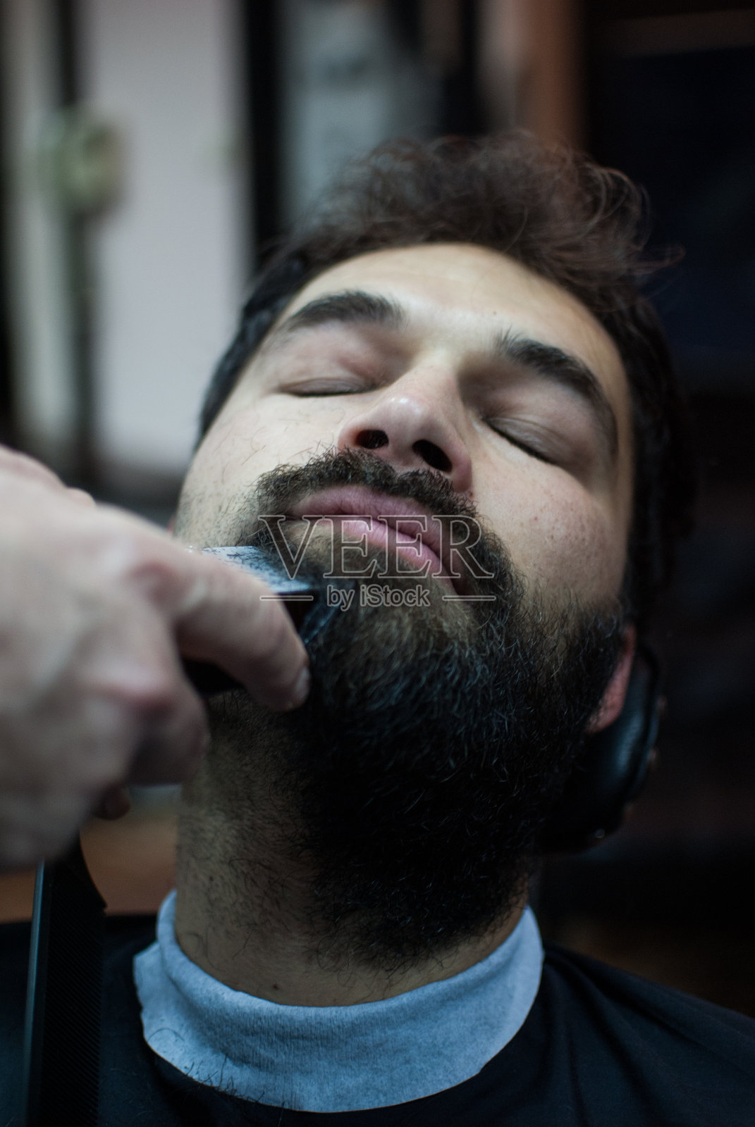 一个英俊的男人在理发店里修剪他的长胡子照片摄影图片