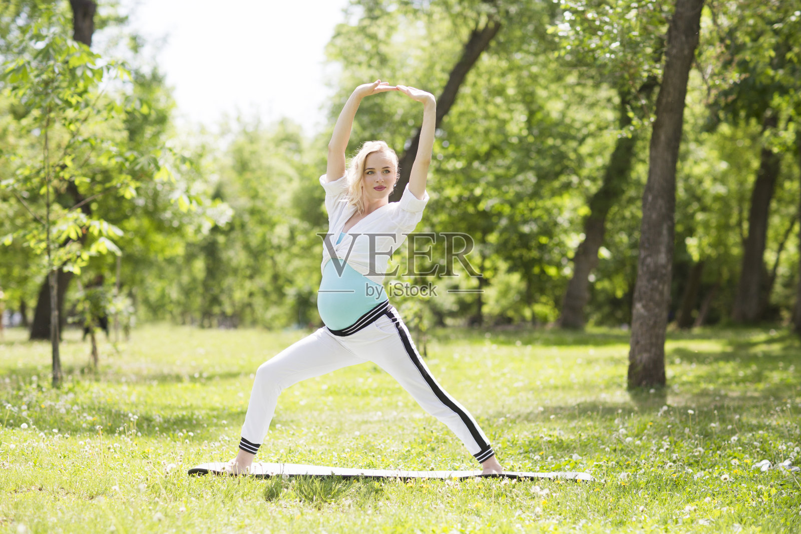 一个年轻的孕妇正在公园里做伸展运动和瑜伽。一个健康的生活照片摄影图片