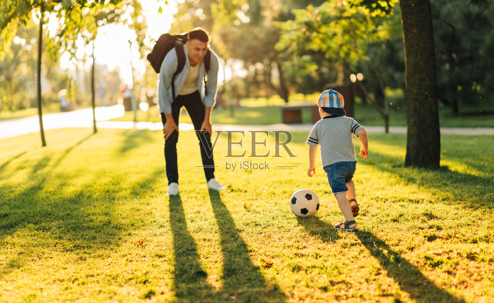 快乐的孩子和爸爸在公园里踢足球，一边慢跑一边玩得开心照片摄影图片