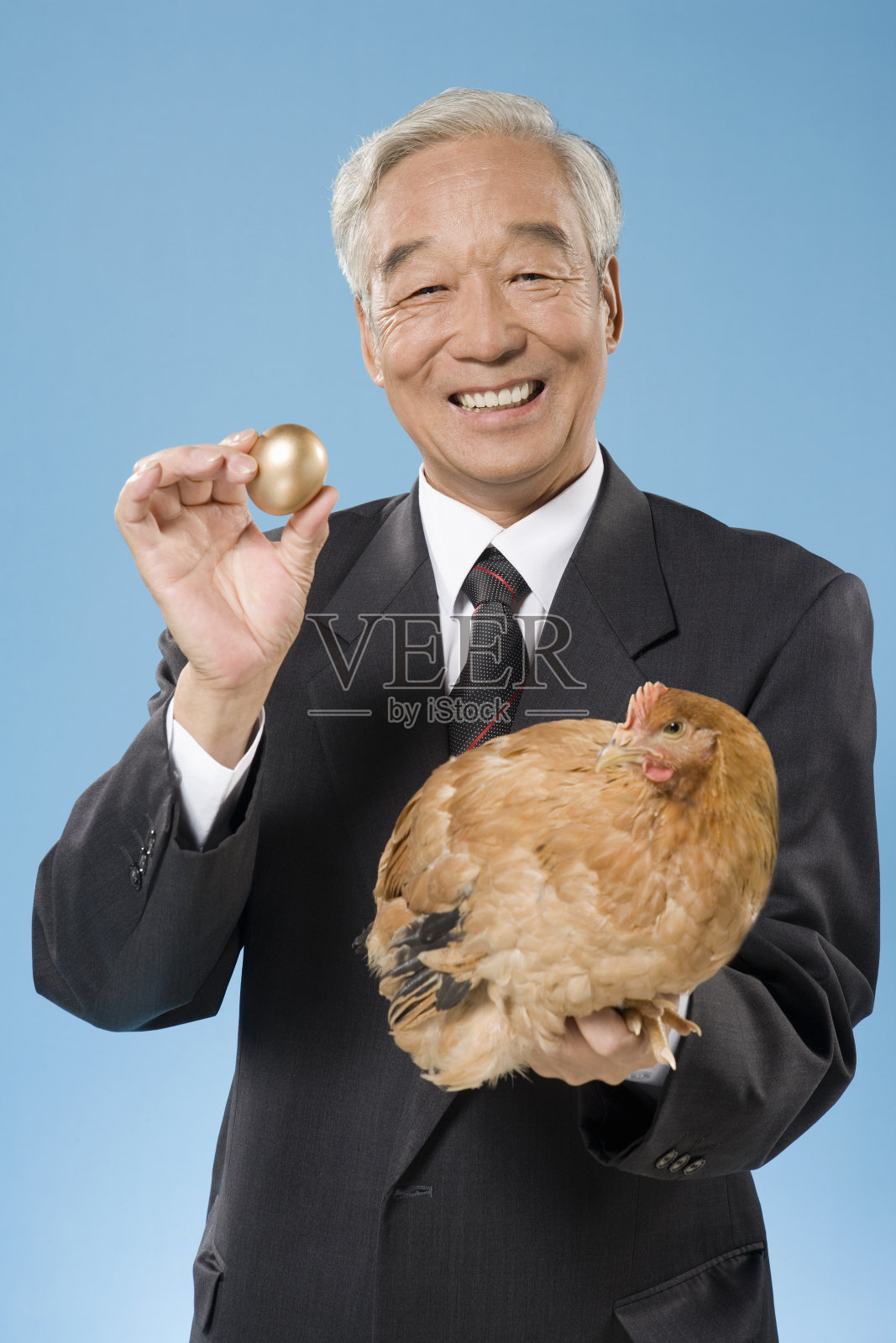 一位老人抱着一只鸡和一个金蛋照片摄影图片