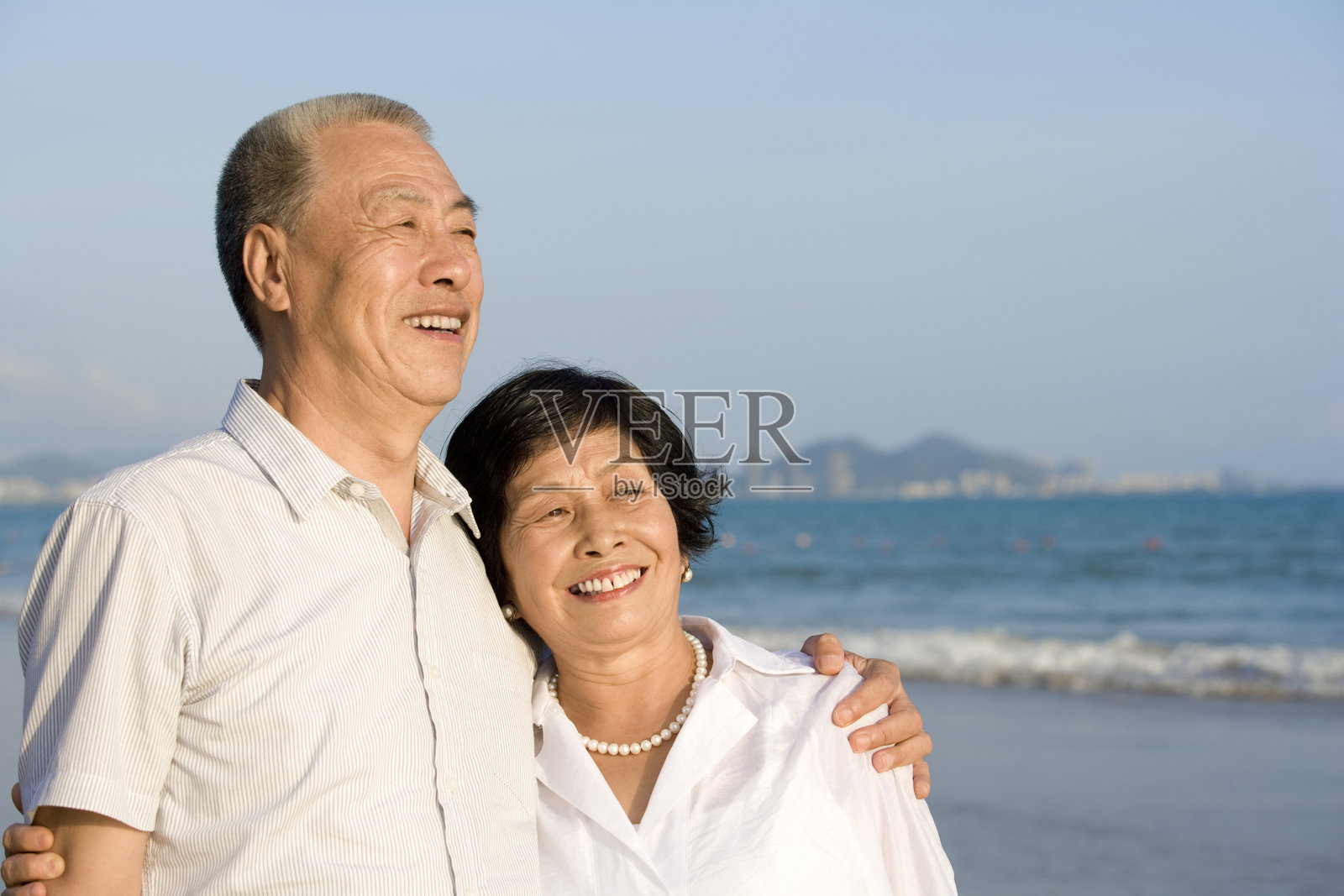老年夫妇在海滩拥抱照片摄影图片
