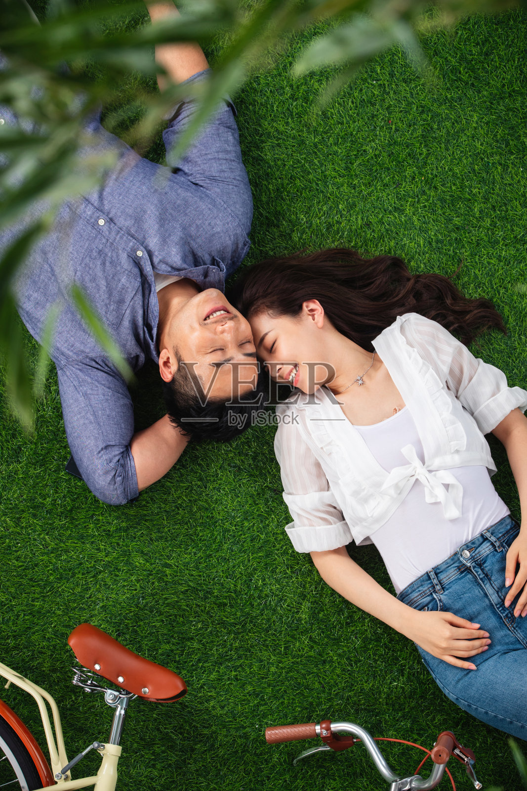 幸福的青年伴侣躺在草地上享受亲密时光照片摄影图片