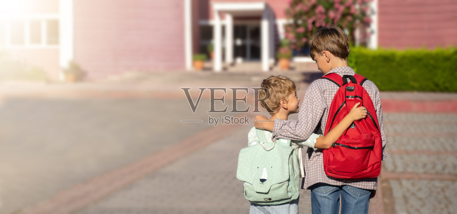 孩子们背着书包回学校。拥抱，微笑，积极向上照片摄影图片