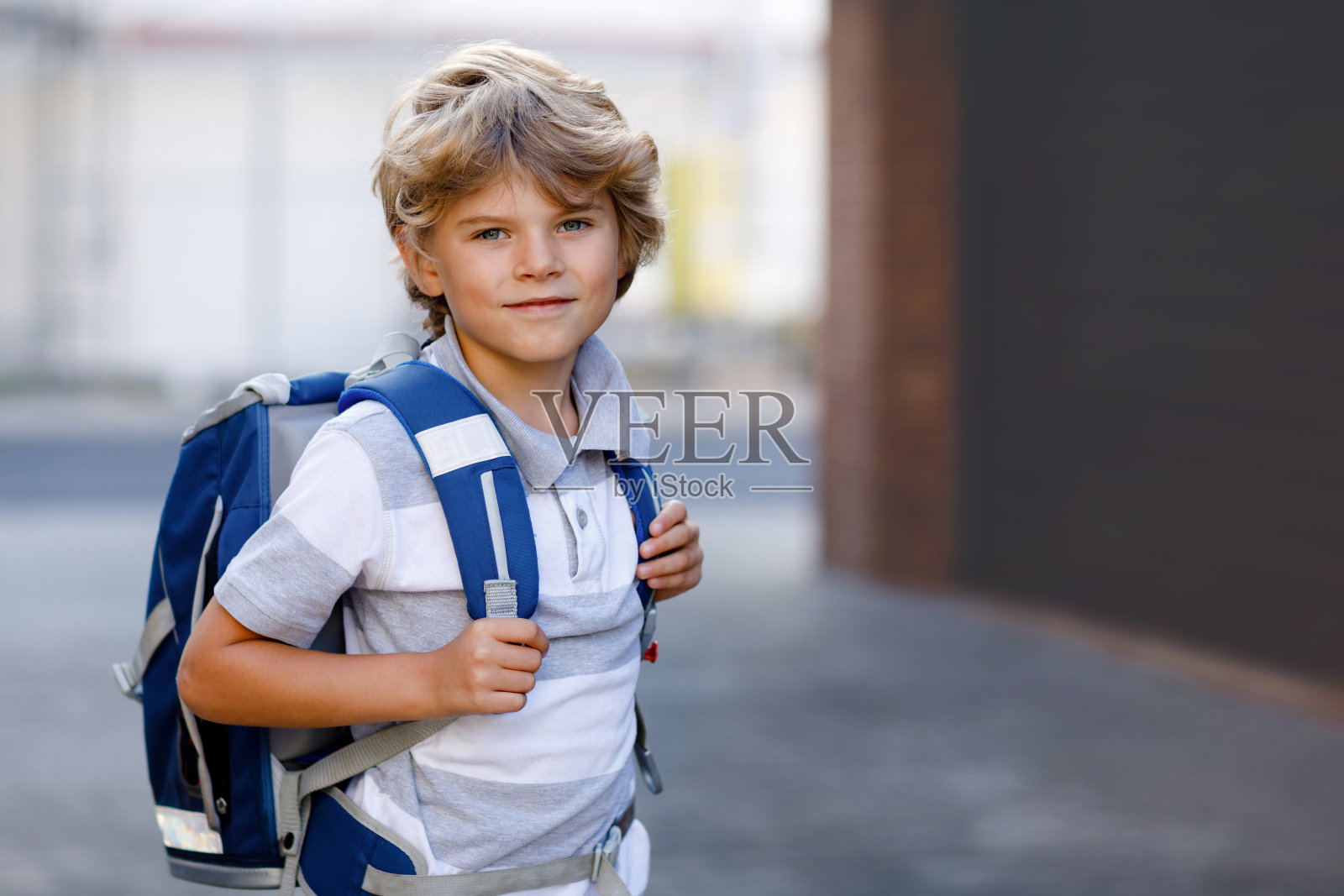 快乐的小男孩带着德语中叫做Ranzen的背包或挎包。上学路上的孩子。户外健康可爱的孩子肖像。学生，学生，回学校去。小学时代照片摄影图片