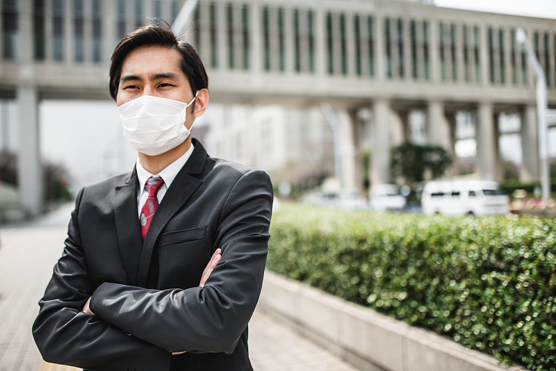一个日本商人戴着污染口罩站在城市里图片下载